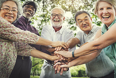 Group of elderly people holding each other hands while smiling