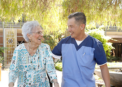 Elderly woman walking alongside with the caregiver