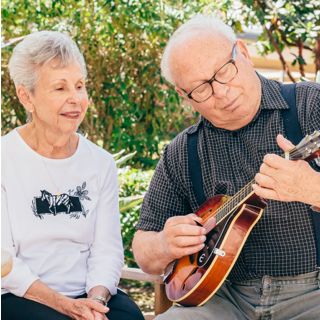 Man playing a mandolin while a woman watches