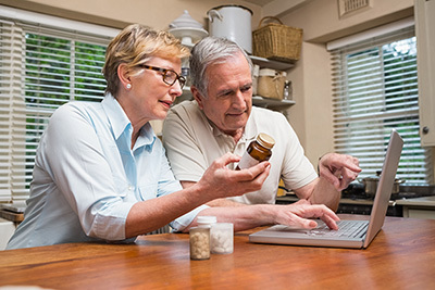 Man and woman looking at medication and computer screen