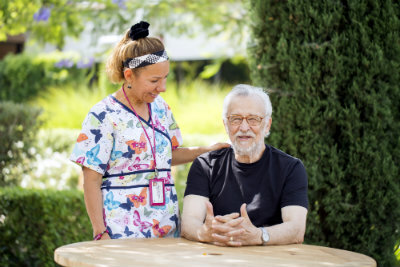 Elderly man seating with a nurse beside him