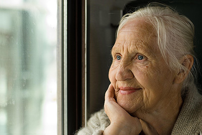Elderly woman looking outside the window