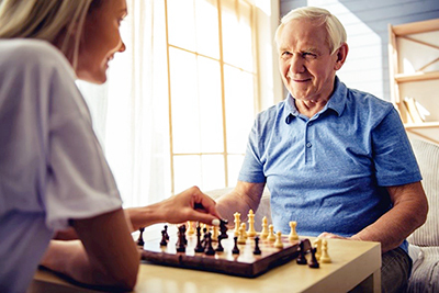Old man playing chess with a nurse
