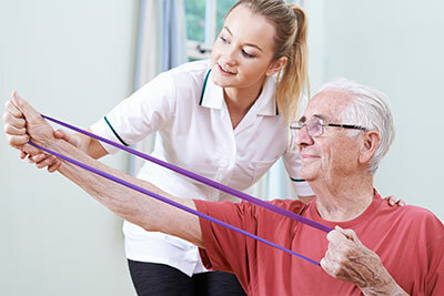 Elderly man with a nurse while holding a rubber for arm therapy.