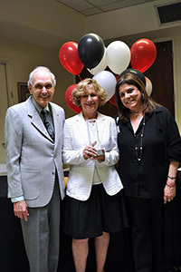 Three people standing with balloons behind them